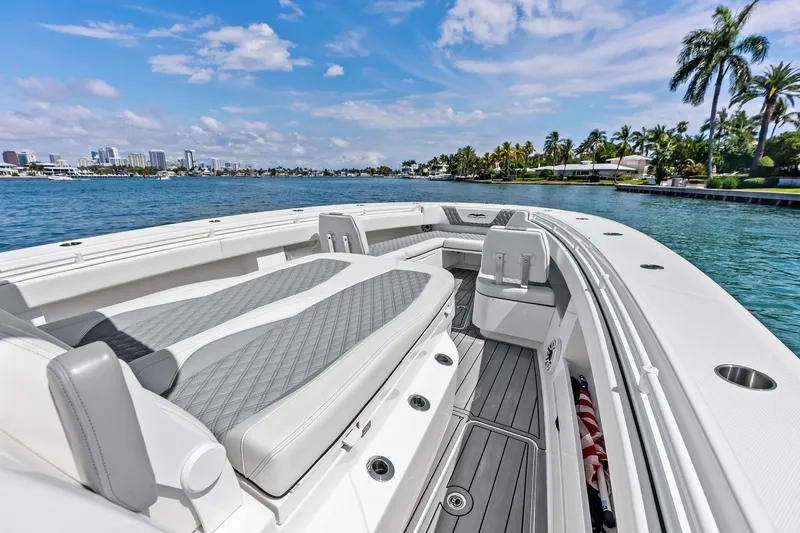 Slide: The Image of 2024 Invincible 43 Open Fisherman boat on scenic waterfront with palm trees and city skyline. - 31