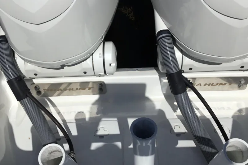 Slide: The Image of 2024 Sea Hunt Gamefish 28 Coffin Box boat engine area with visible hoses and branding. - 40