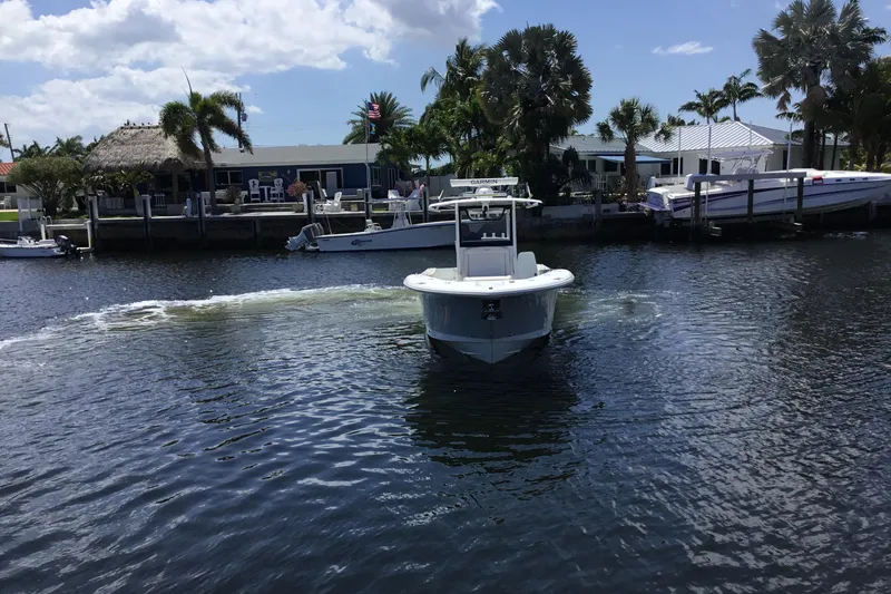 Slide: The Image of 2024 Sea Hunt Gamefish 28 Coffin Box boat navigating a scenic waterfront area. - 7