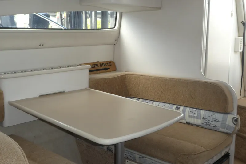 Slide: The Image of Interior of 2002 Bayliner 2855 Ciera boat with cozy dining area and cushioned seating. - 11