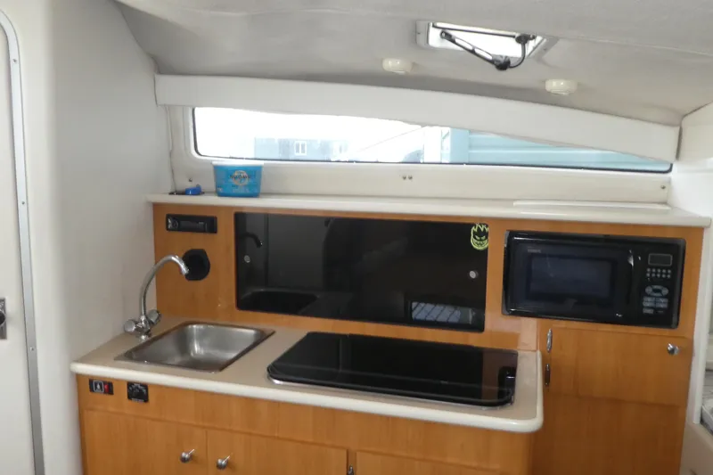 Slide: The Image of Interior of 2002 Bayliner 2855 Ciera boat featuring kitchenette with sink, stove, and microwave. - 8