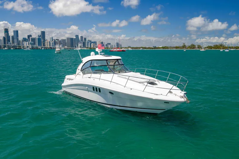 The Image of 2009 Sea Ray 40 Sundancer yacht cruising in turquoise waters near a city skyline. - 0