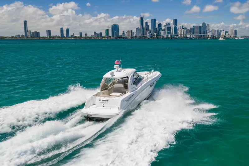 Slide: The Image of 2009 Sea Ray 40 Sundancer cruising in turquoise waters with city skyline backdrop. - 14