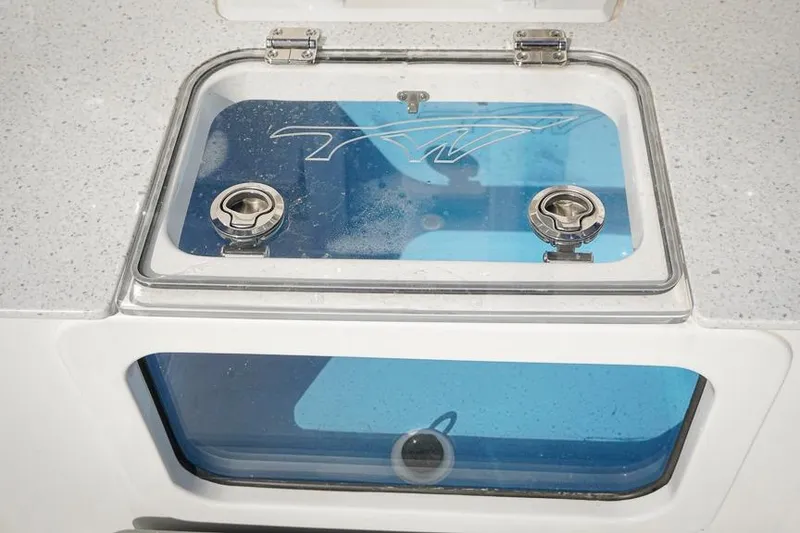 Slide: The Image of Livewell compartment on 2026 Tidewater 3100 Carolina Bay boat, featuring secure latches and clear lid. - 32