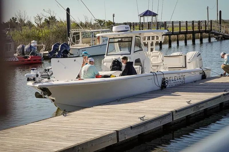 Slide: The Image of 2026 Tidewater 3100 Carolina Bay boat docked with people onboard, sunny day. - 41