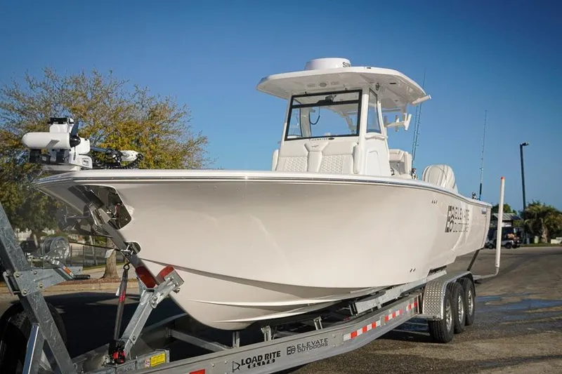 Slide: The Image of 2026 Tidewater 3100 Carolina Bay boat on trailer, parked outdoors under clear blue sky. - 5