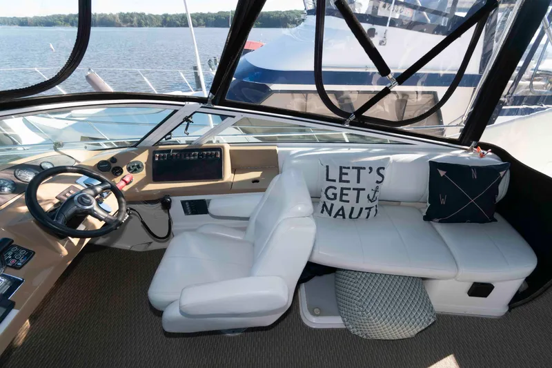 Slide: The Image of 2003 Carver 350 Mariner cockpit with white seating, nautical-themed pillows, and steering wheel. - 9