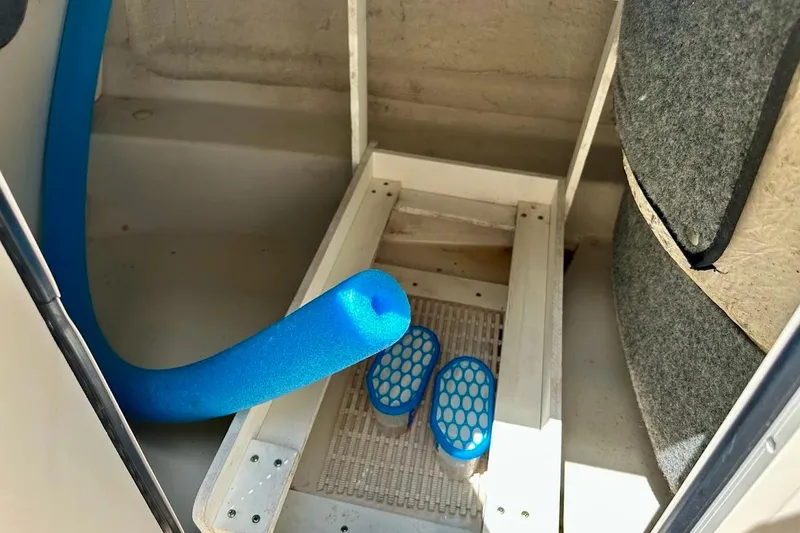 Slide: The Image of Interior of a 2004 Sea Ray 200 Sundeck with blue pool noodle and sandals. - 14