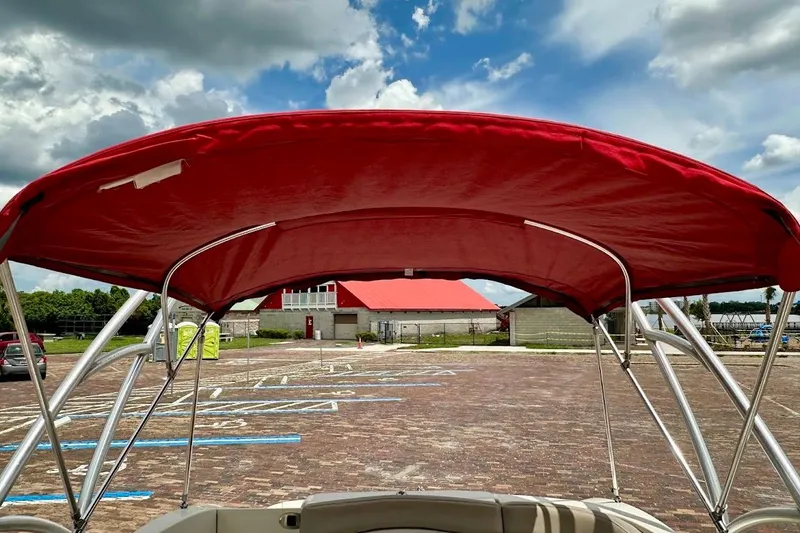 Slide: The Image of Red canopy on 2004 Sea Ray 200 Sundeck boat, parked under a cloudy sky. - 18