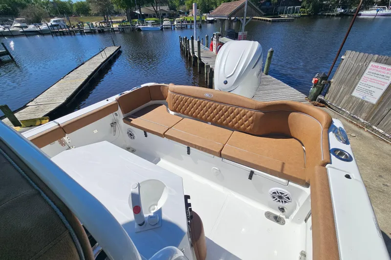 Slide: The Image of 2026 Sea Hunt Ultra 255 SE boat with tan seating, docked by a serene waterfront. - 10