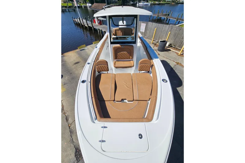 Slide: The Image of 2026 Sea Hunt Ultra 255 SE boat with tan seating, docked by a serene waterfront. - 25