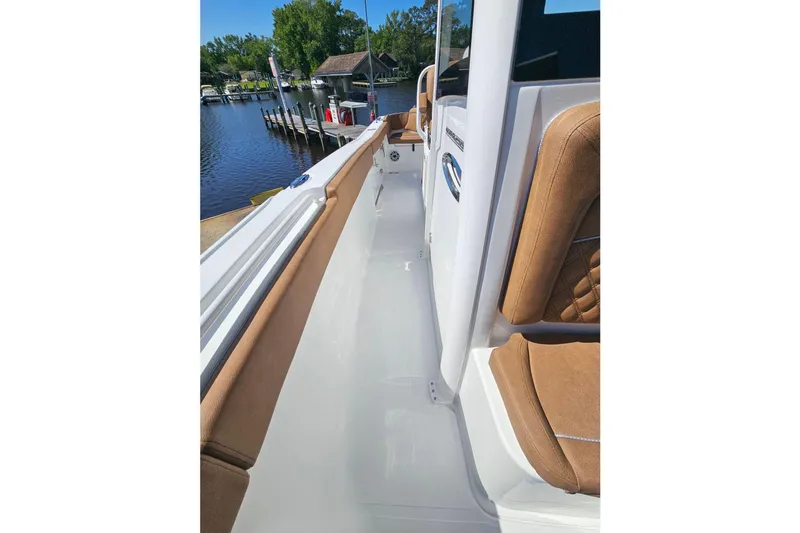 Slide: The Image of 2026 Sea Hunt Ultra 255 SE boat interior with tan seating, docked by a serene waterfront. - 27