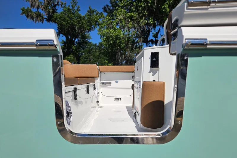 Slide: The Image of 2026 Sea Hunt Ultra 255 SE boat interior with seating and storage, surrounded by lush greenery. - 6