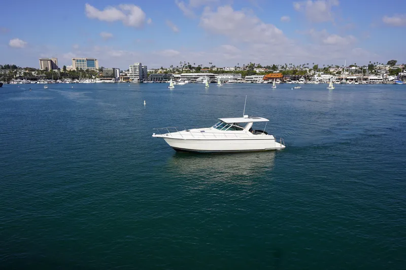 Slide: The Image of 1994 Tiara Yachts 4000 Express cruising in a scenic harbor with city skyline backdrop. - 3