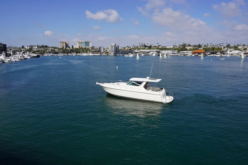 Slide: The Image of 1994 Tiara Yachts 4000 Express cruising in a scenic harbor with city skyline backdrop. - 4
