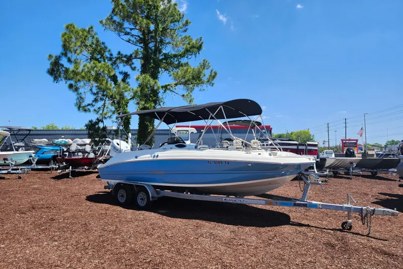 The Image of 2024 Stingray 212 SC boat on trailer, parked outdoors under clear blue sky. - 1