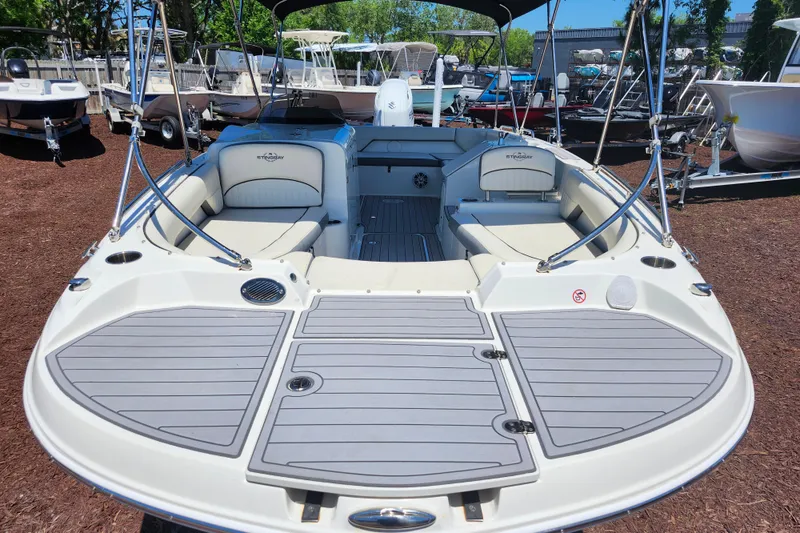 Slide: The Image of 2024 Stingray 212 SC boat with spacious seating and sleek design in a marina setting. - 10