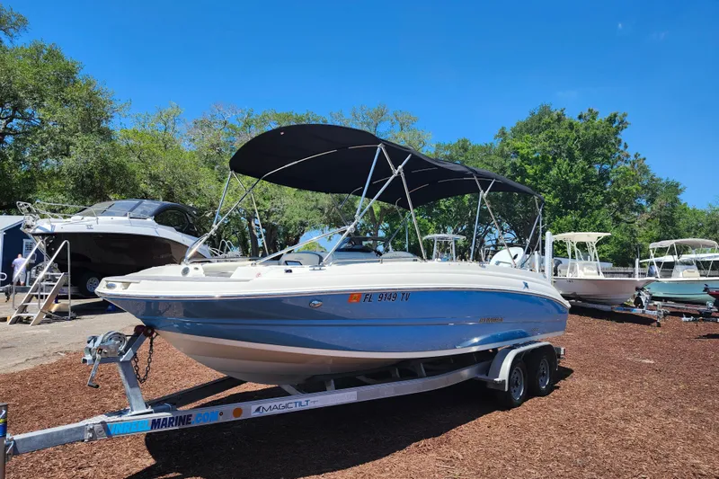 Slide: The Image of 2024 Stingray 212 SC boat on trailer, parked outdoors under clear blue sky. - 3