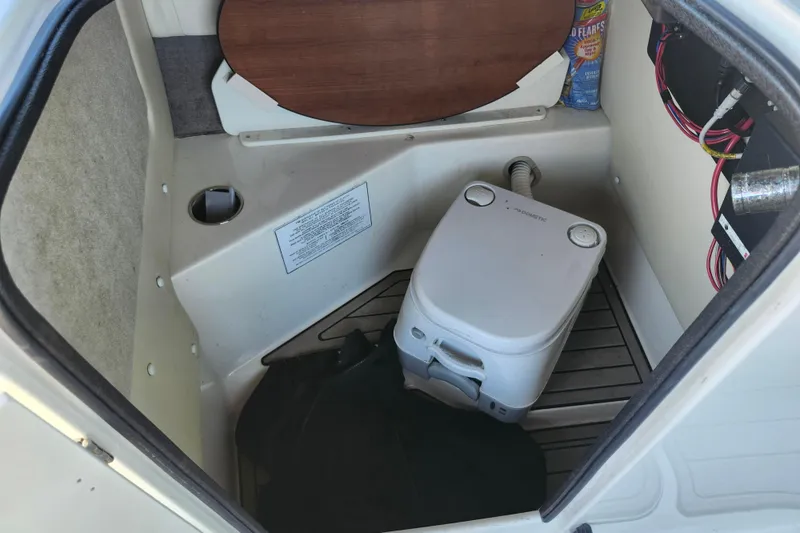 Slide: The Image of 2024 Stingray 212 SC boat interior with portable toilet and storage area. - 31