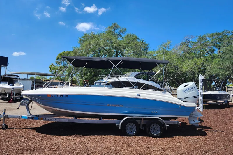 Slide: The Image of 2024 Stingray 212 SC boat on trailer, parked outdoors under clear blue sky. - 4