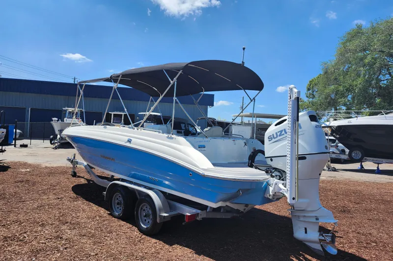 Slide: The Image of 2024 Stingray 212 SC boat with Suzuki outboard motor on trailer, under blue sky. - 5