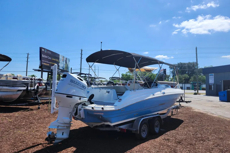 Slide: The Image of 2024 Stingray 212 SC boat with Suzuki outboard motor on trailer, under clear blue sky. - 7