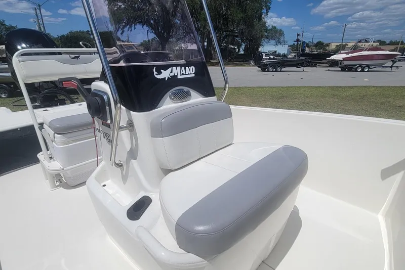 Slide: The Image of 2024 Mako Pro Skiff 17 CC boat interior with seating and console, under a clear blue sky. - 10