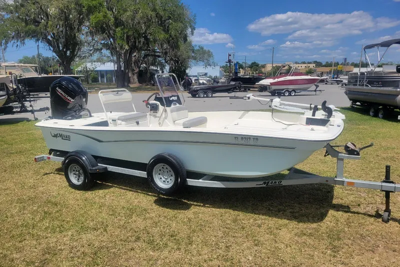 Slide: The Image of 2024 Mako Pro Skiff 17 CC boat on trailer, parked on grass under blue sky. - 3