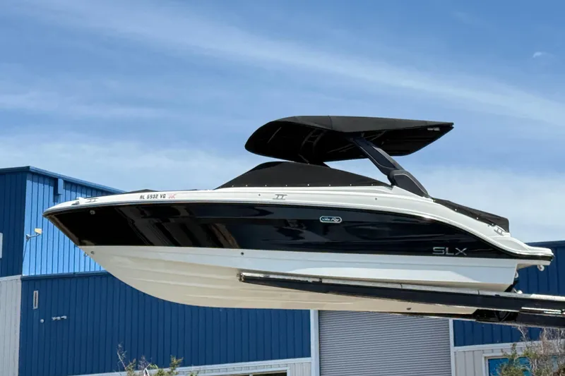 The Image of 2023 Sea Ray SLX 260 boat with sleek black and white design, docked near blue building. - 1