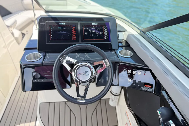 Slide: The Image of 2023 Sea Ray SLX 260 helm with dual Simrad displays and modern steering wheel. - 12