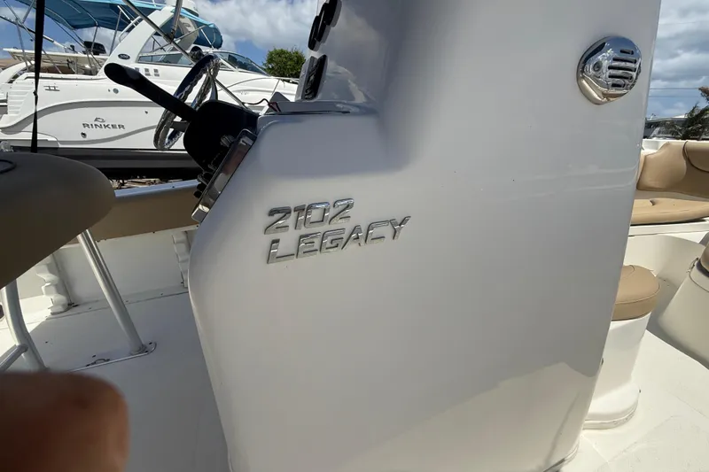 Slide: The Image of 2019 NauticStar 2102 Legacy boat with tan seating, docked under a partly cloudy sky. - 13