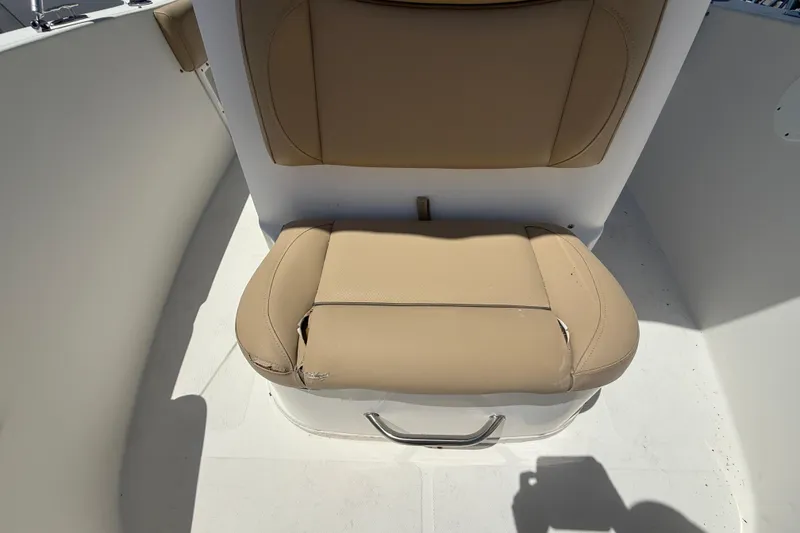 Slide: The Image of 2019 NauticStar 2102 Legacy boat interior with beige seating, docked near other boats. - 14