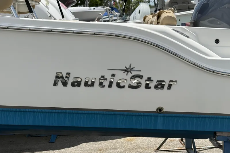 Slide: The Image of 2019 NauticStar 2102 Legacy boat with tan seating, parked among other boats. - 3