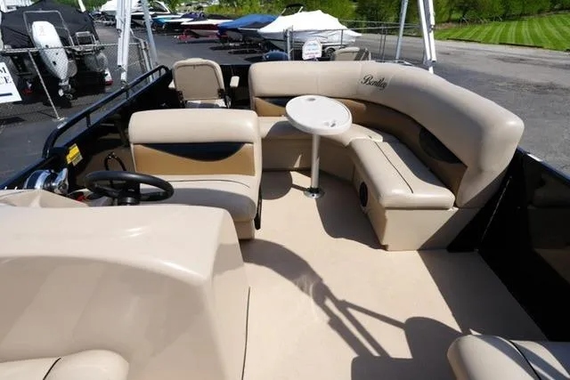 Slide: The Image of 2017 Bentley 244 pontoon boat interior with beige seating and small table. - 10