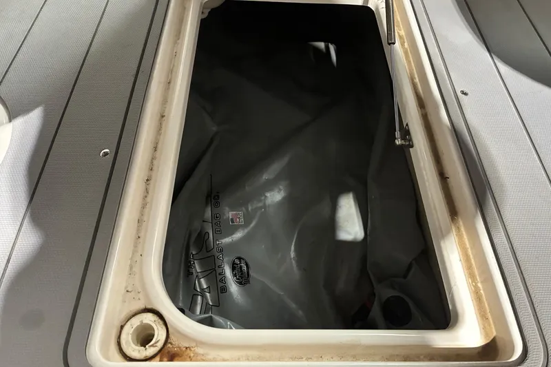 Slide: The Image of Open storage compartment on 2020 Chaparral 25 Surf boat with ballast bag inside. - 23