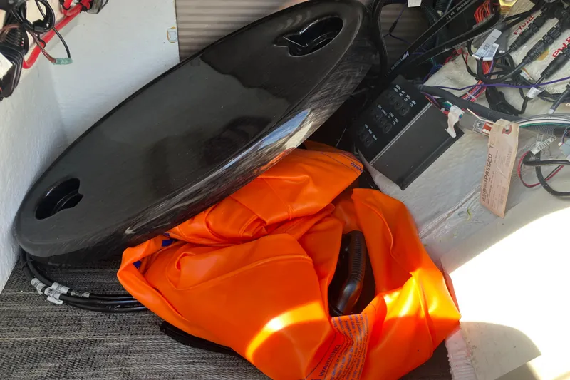 Slide: The Image of Storage compartment in 2023 Godfrey Monaco 255 SB with orange life jacket and black cover. - 11