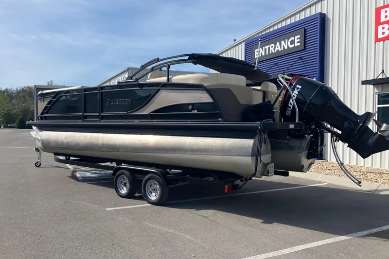 Slide: The Image of 2023 Godfrey Monaco 255 SB pontoon boat on trailer, parked outside a building. - 2