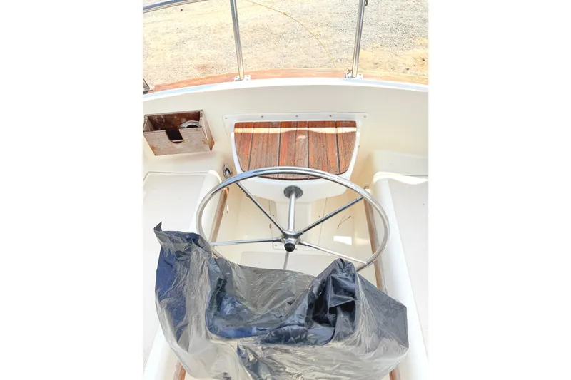 Slide: The Image of 1984 Island Packet boat helm with steering wheel and covered seat. - 13