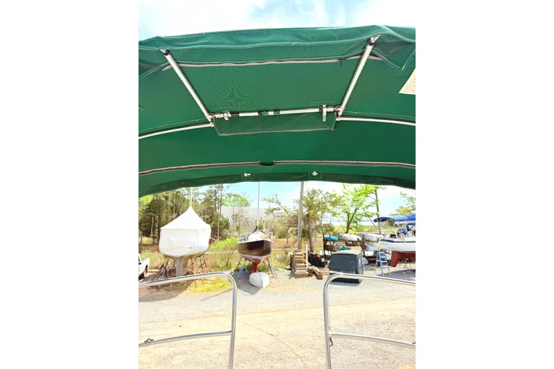 Slide: The Image of 1984 Island Packet sailboat with green canopy in a boatyard setting. - 14