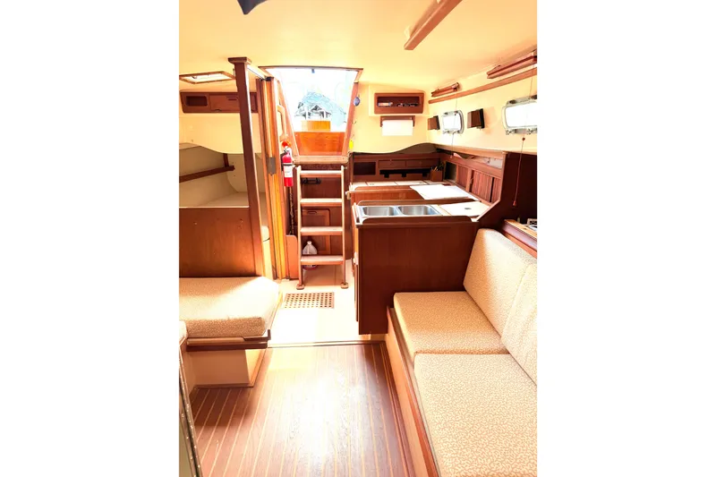 Slide: The Image of Interior of a 1984 Island Packet sailboat, featuring cozy seating and a compact kitchen area. - 17
