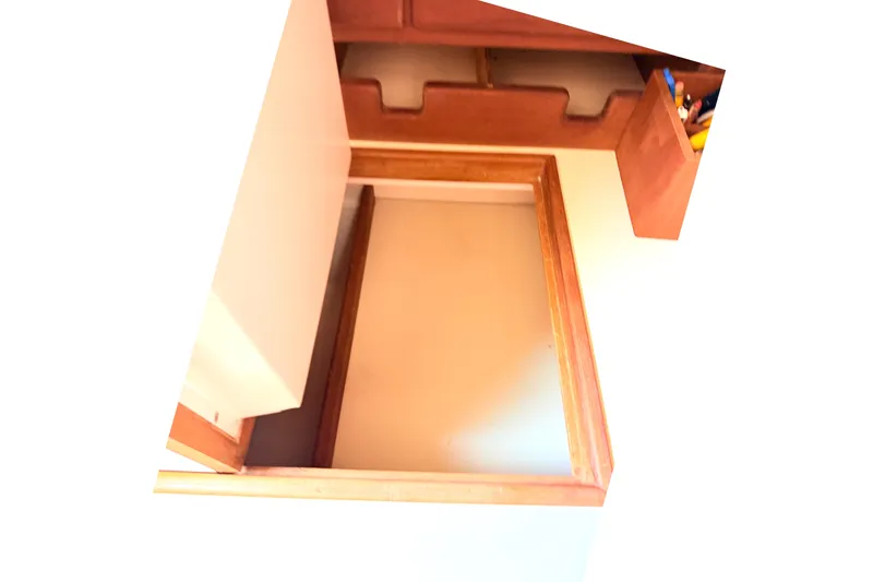 Slide: The Image of Interior storage compartment on a 1984 Island Packet boat, featuring wooden trim and shelves. - 29