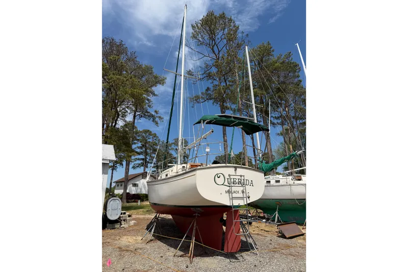Slide: The Image of 1984 Island Packet sailboat on land, surrounded by trees, under a clear blue sky. - 43