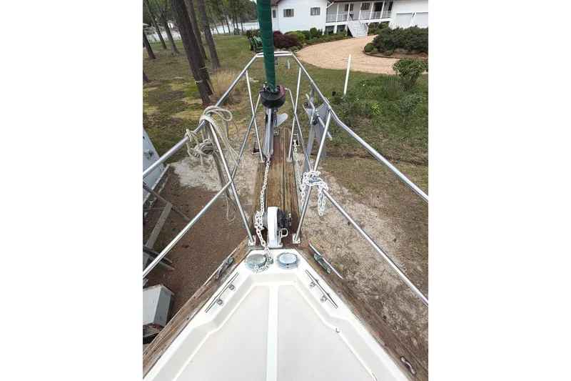 Slide: The Image of 1984 Island Packet sailboat bow with anchor and ropes, docked near a house. - 5