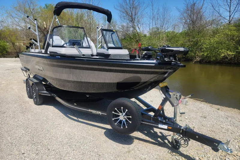 Slide: The Image of 2026 Smoker Craft Adventurer 210 GLS Sport boat on trailer by a riverbank. - 12
