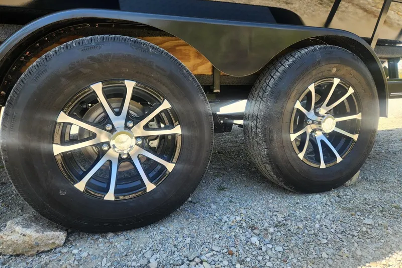 Slide: The Image of 2026 Smoker Craft Adventurer 210 GLS Sport trailer wheels on gravel surface. - 15
