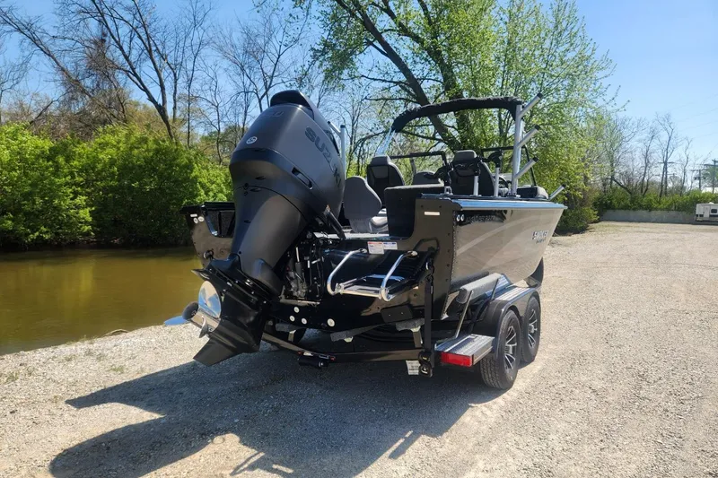 Slide: The Image of 2026 Smoker Craft Adventurer 210 GLS Sport boat on trailer by a riverbank. - 17