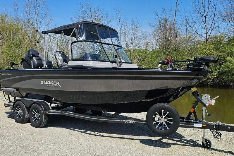 Slide: The Image of 2026 Smoker Craft Adventurer 210 GLS Sport boat on trailer by a riverbank. - 2