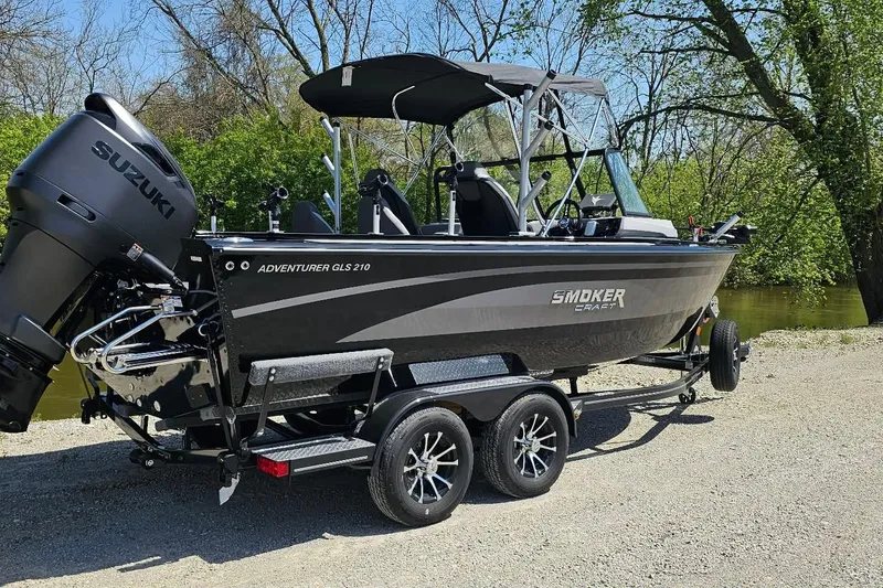 Slide: The Image of 2026 Smoker Craft Adventurer 210 GLS Sport boat on trailer, parked near a river. - 5
