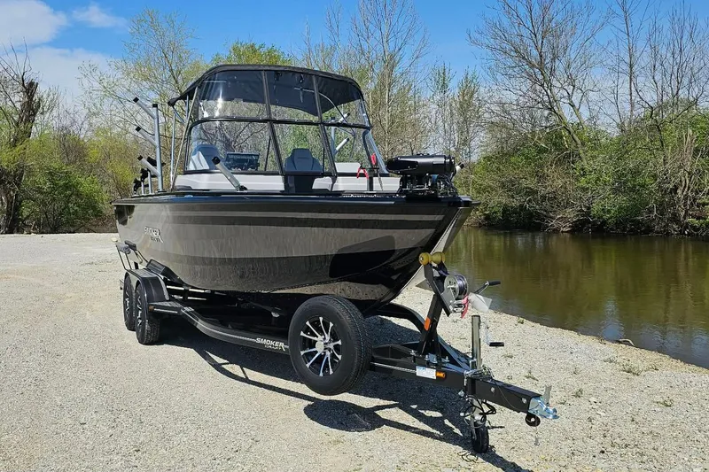 Slide: The Image of 2026 Smoker Craft Adventurer 210 GLS Sport boat on trailer by a riverbank. - 6