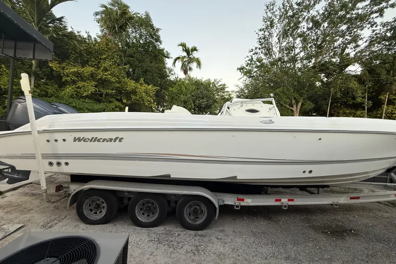 The Image of 2004 Wellcraft 32 CCF boat on trailer, surrounded by lush greenery. - 1